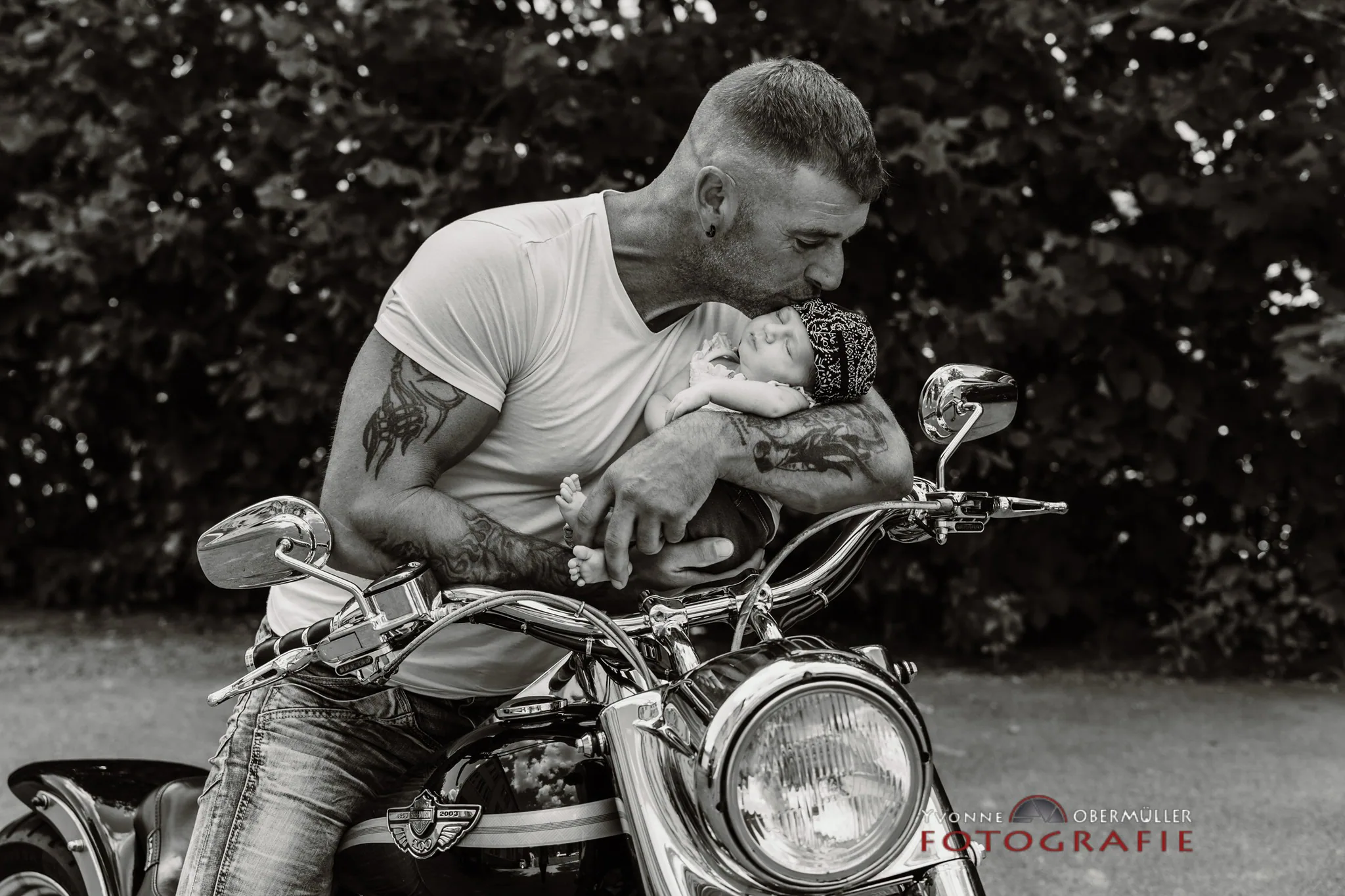 Vater küsst sein neugeborenes Baby auf einem Motorrad