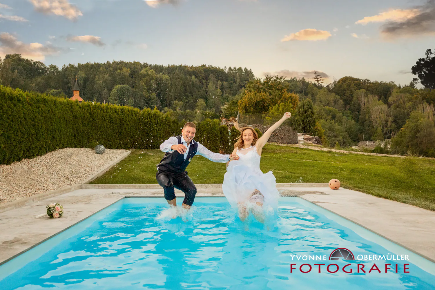 Braut und Bräutigam springen gemeinsam in einen Pool